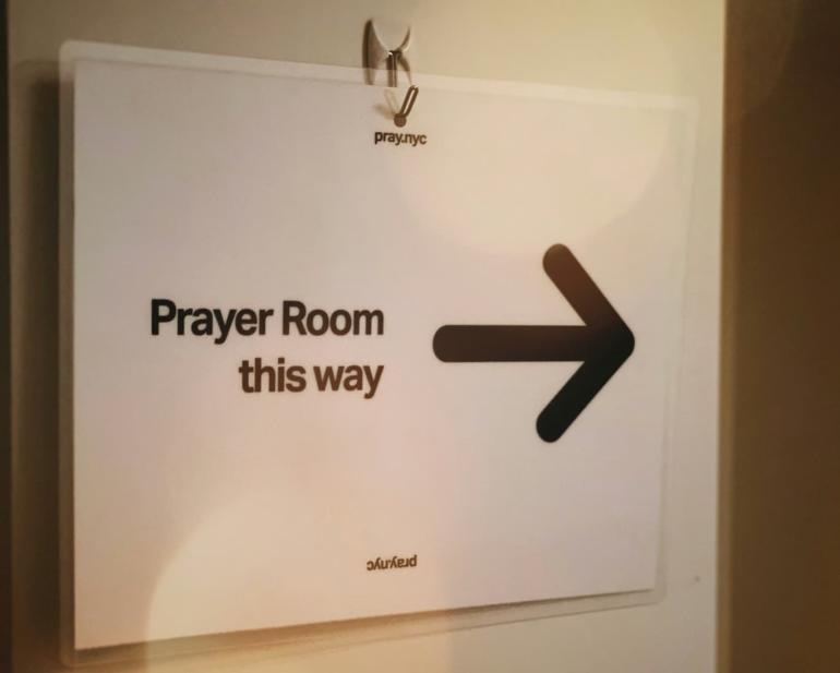 Znak s puščico za sobo za molitev – “Prayer Room this way”.